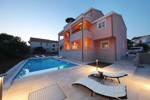 Ein zweistöckiges Haus mit Swimmingpool und Außenbereich mit Sitzgelegenheiten.
