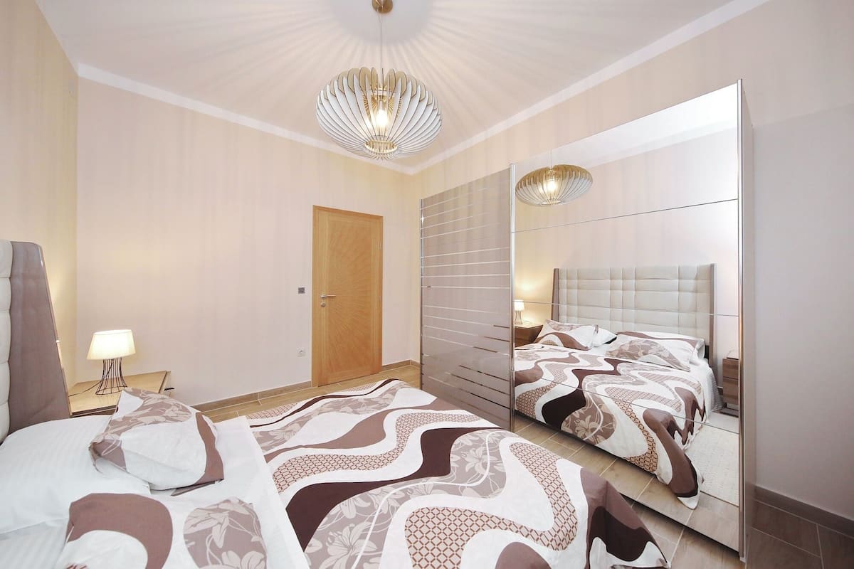 Een moderne hotelkamer met een groot bed, een spiegel en een kroonluchter.