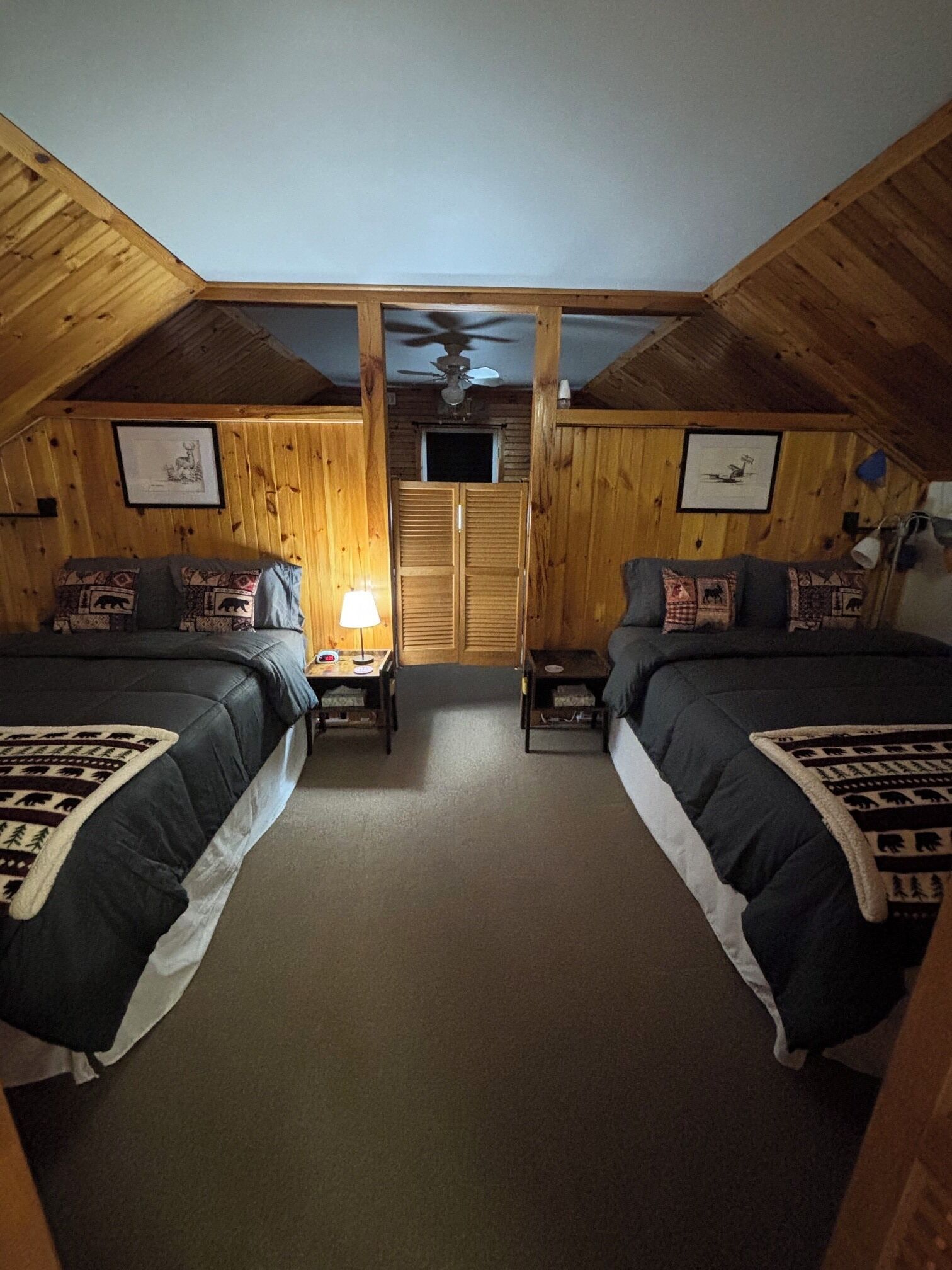 A room with two beds, a ceiling fan, and a TV.