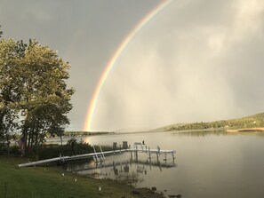 Järvi, jossa on laituri, puita ja sateenkaari.