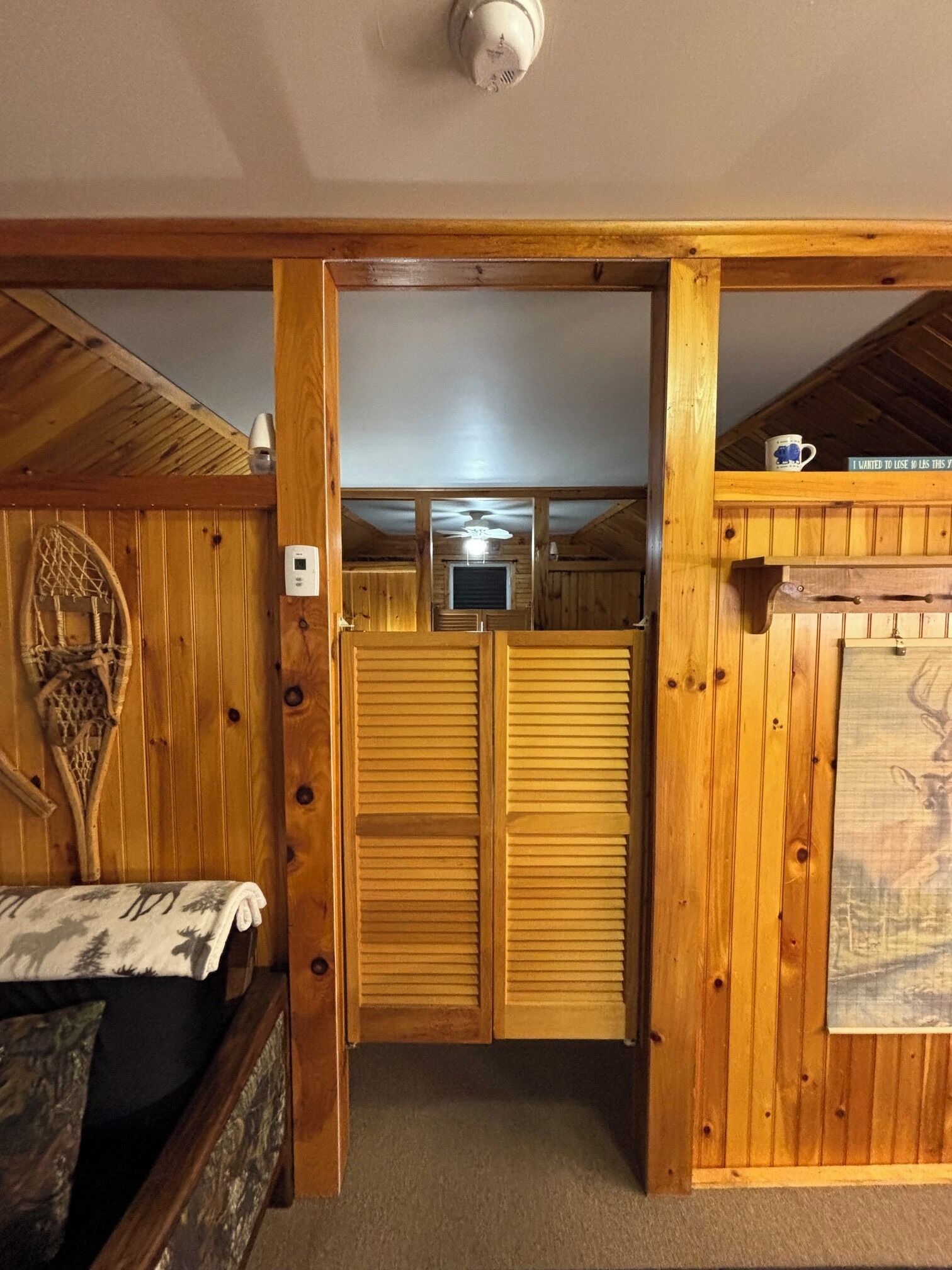 A wooden interior with a closed door, a ceiling fan, and a mounted television.