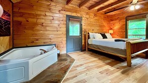 Una cabaña con interior de madera, una cama, una bañera y un ventilador de techo.