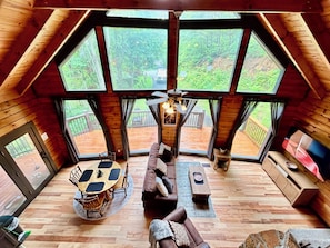 A spacious loft with a high ceiling, large windows, a dining area, and a cozy seating area.