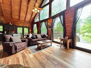A spacious wooden cabin with a large sofa, coffee table, and dining area.