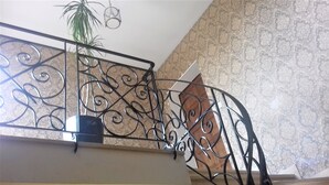 Una escalera con barandilla de metal decorada con motivos de volutas.