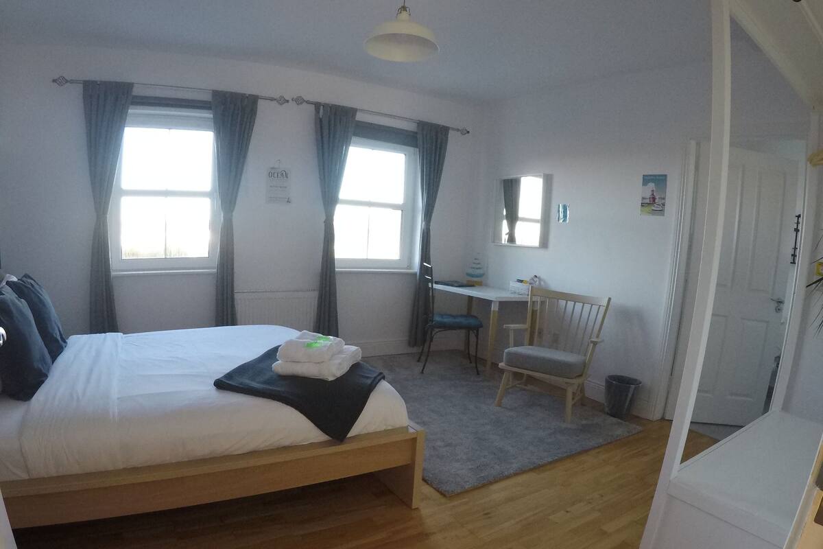 Quarto com cama, escrivaninha e cadeira.
