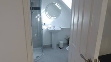 A bathroom with a glass shower, a round mirror, and a sink.