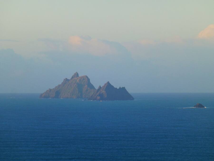 A coastal landscape with a prominent rocky island and a smaller island in the distance.