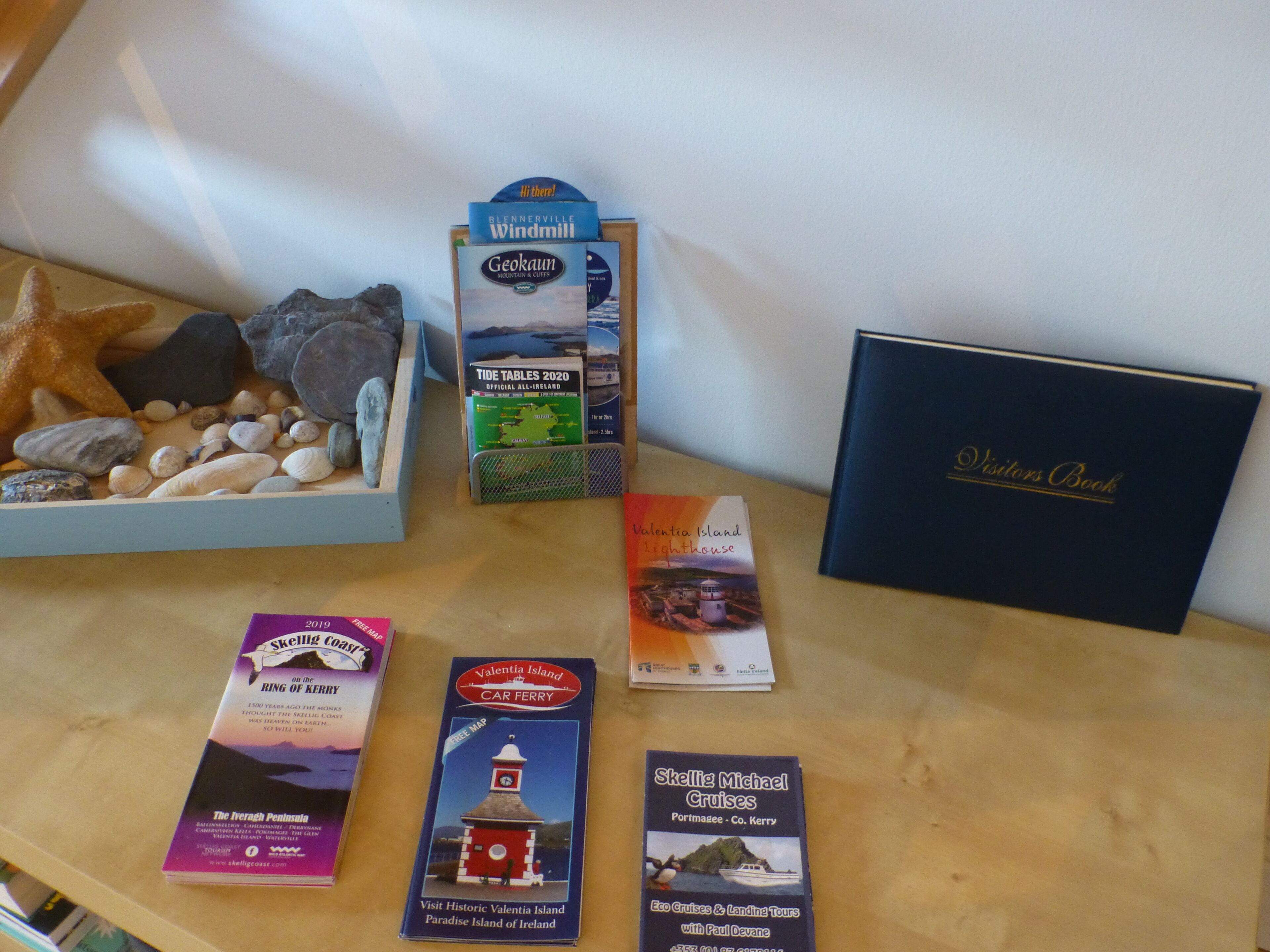 A collection of travel brochures and maps on a wooden surface.