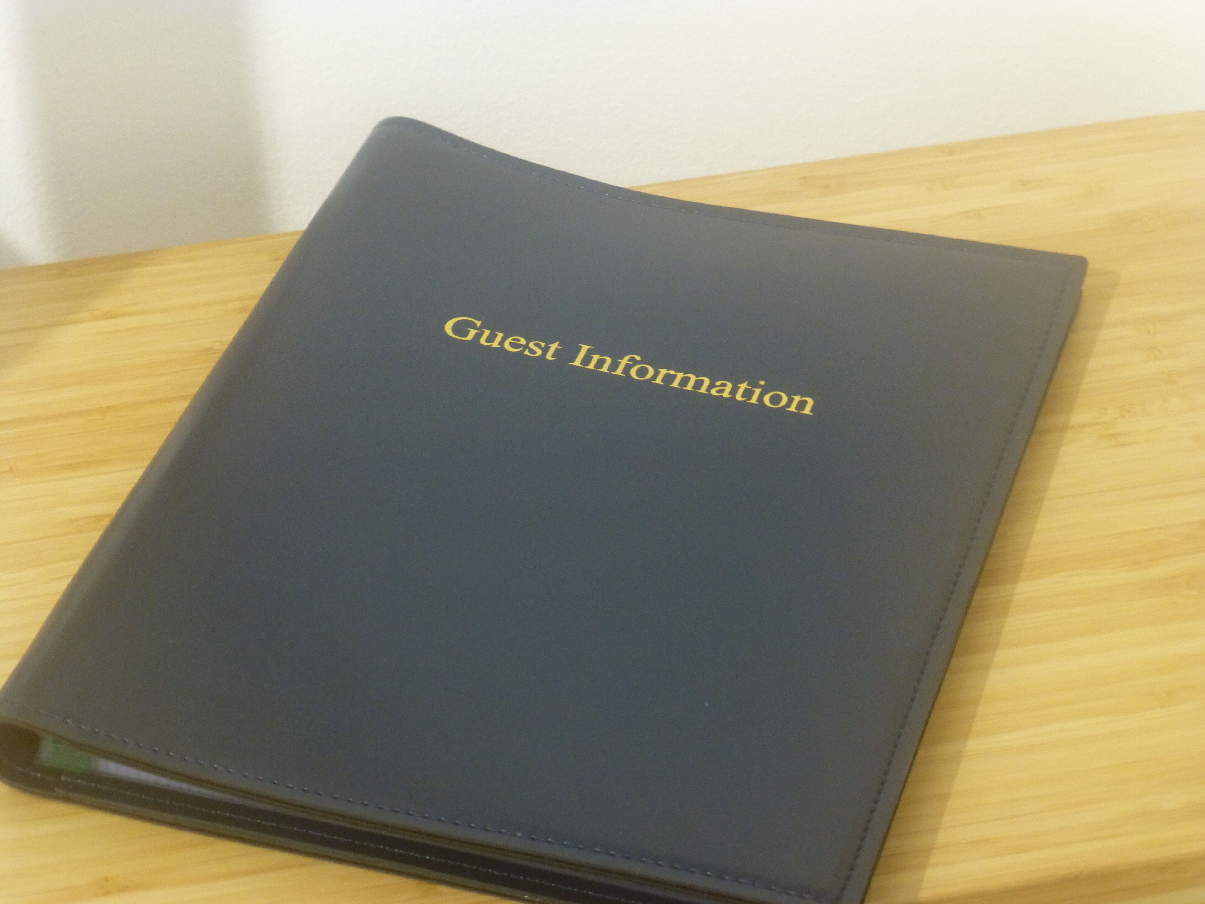 Un classeur bleu foncé sur lequel est inscrit en lettres dorées : « Informations pour les invités ».