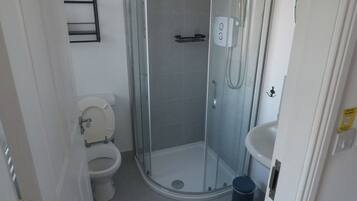 Un baño con ducha de vidrio, inodoro y lavamanos.