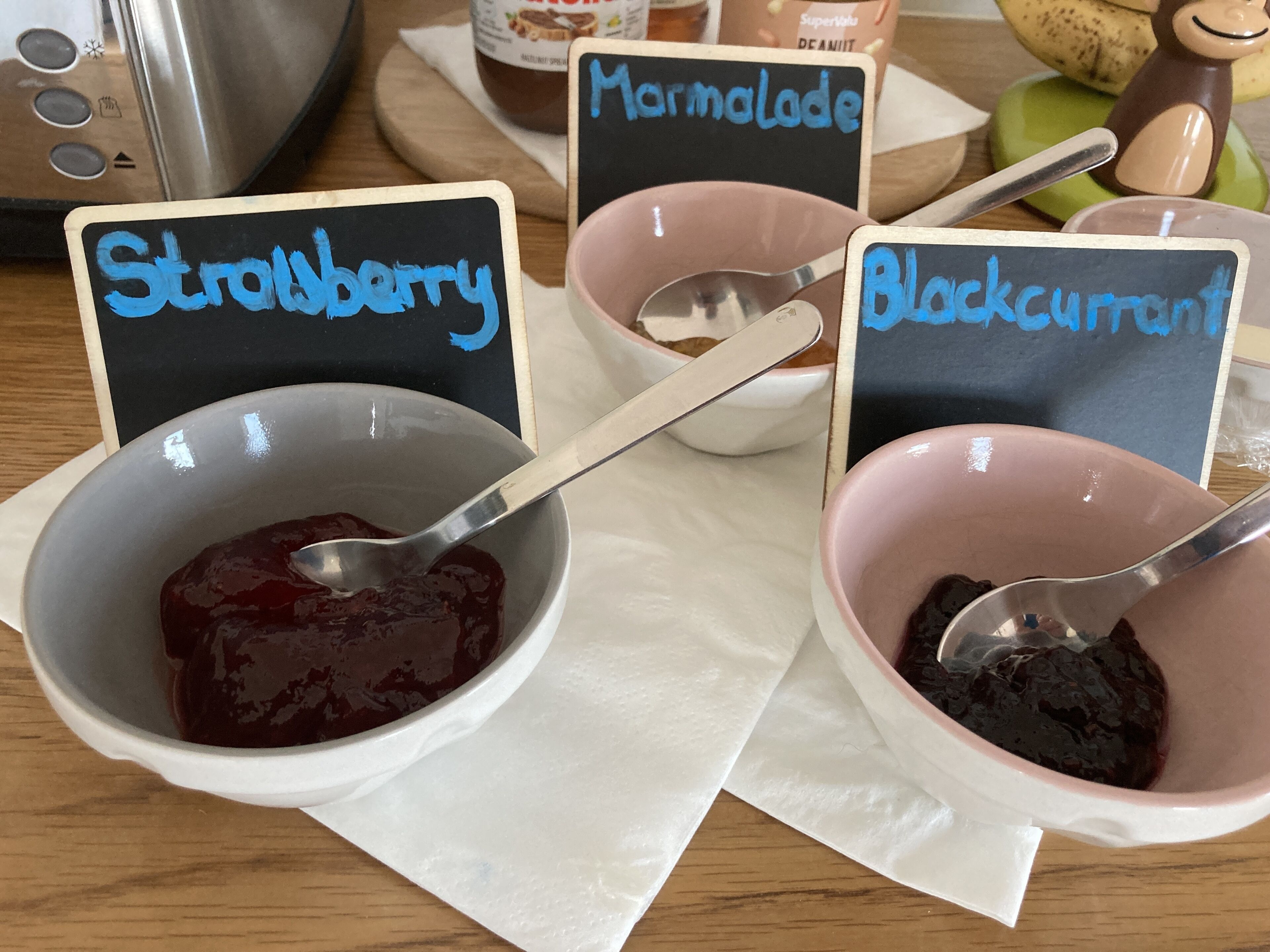 Trois pots de confiture, chacun portant une étiquette indiquant « Fraise », « Marmelade » et « Cassis ».