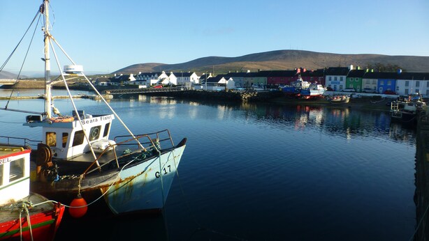 A harbor with boats, a lighthouse, and colorful buildings in the background. - Seagull Cottage B&B (Portmagee)