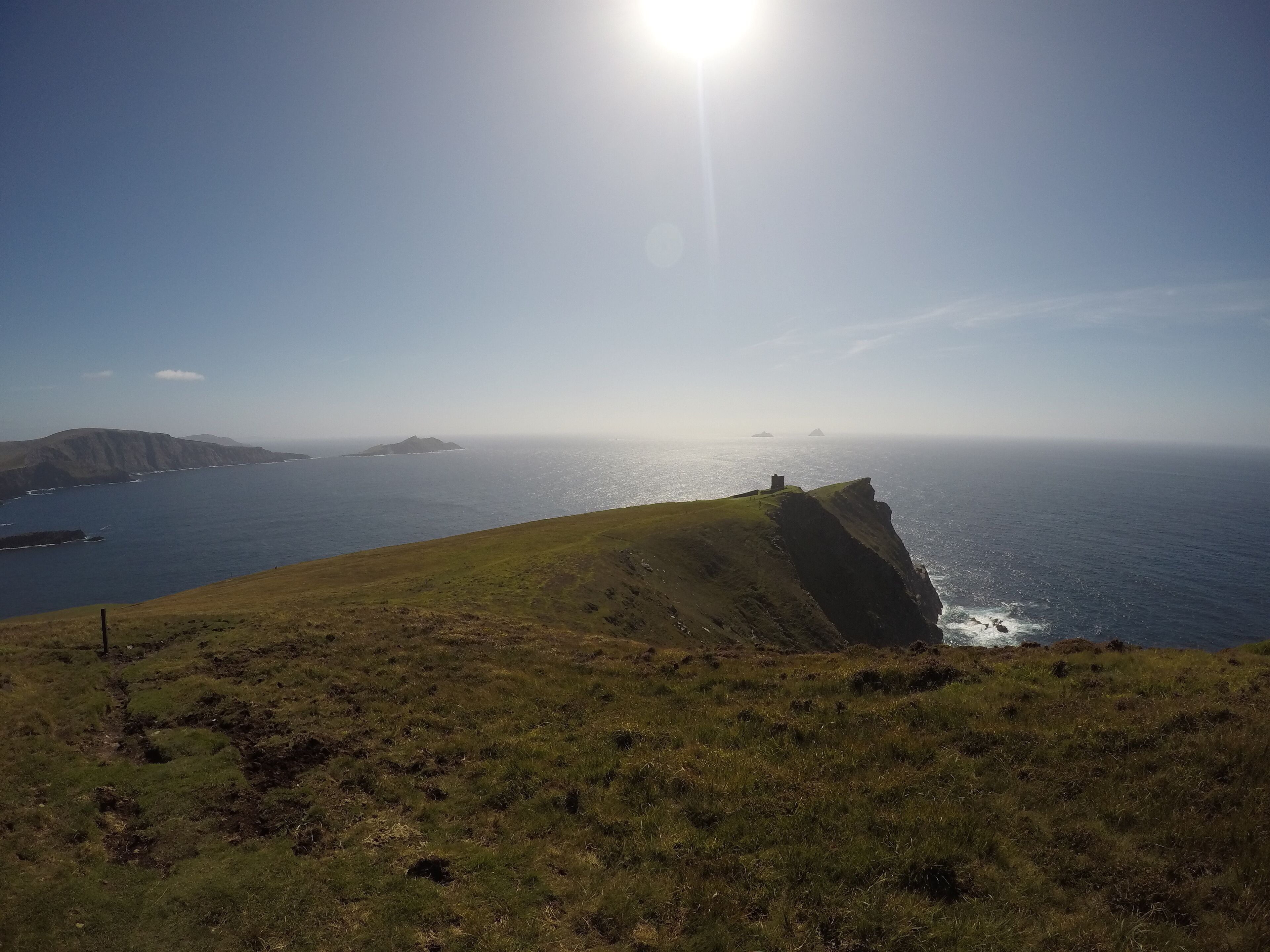 A coastal landscape with a grassy hill and cliffs overlooking the sea.