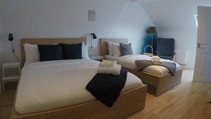 A modern hotel room with two beds, a small table, and a lamp. - Seagull Cottage B&B (Portmagee)