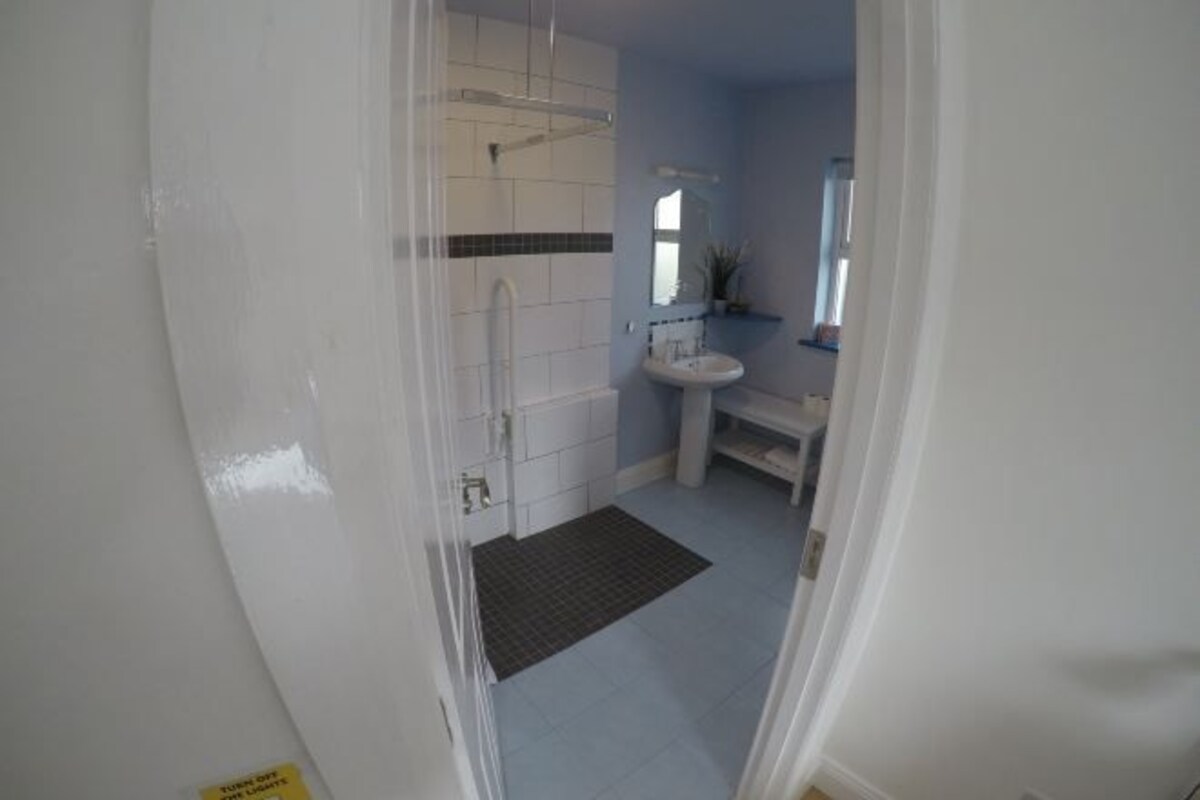 Un baño con azulejos blancos, ducha, lavabo y espejo.
