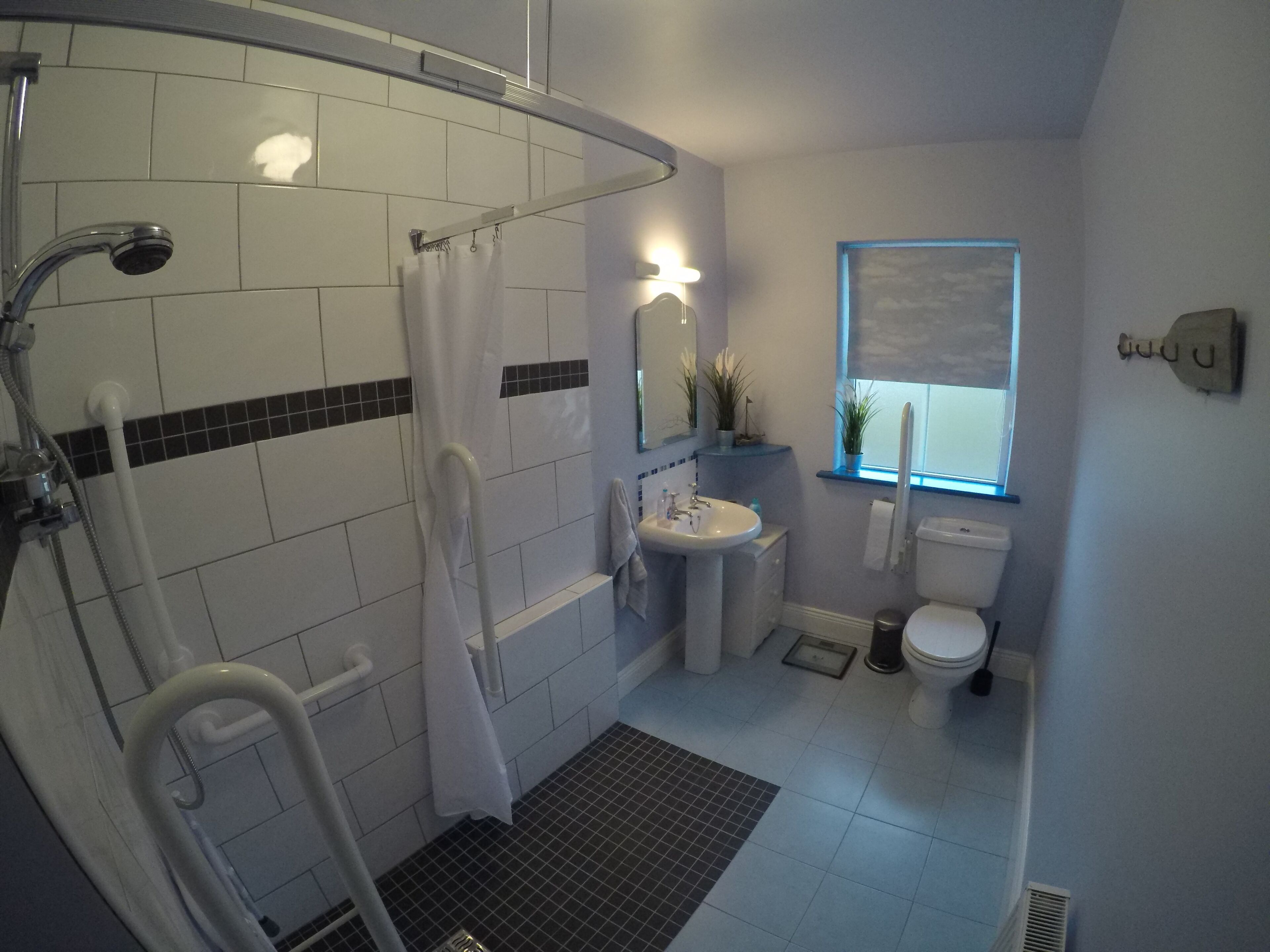 A bathroom with a shower, sink, toilet, and a window.