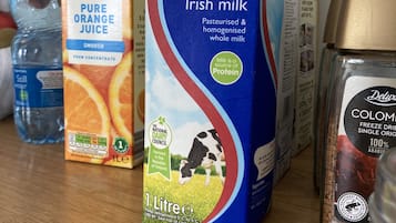 Een karton SuperValu Fresh Ierse melk, een fles Pure sinaasappelsap en een fles stilstaand water op een tafel.