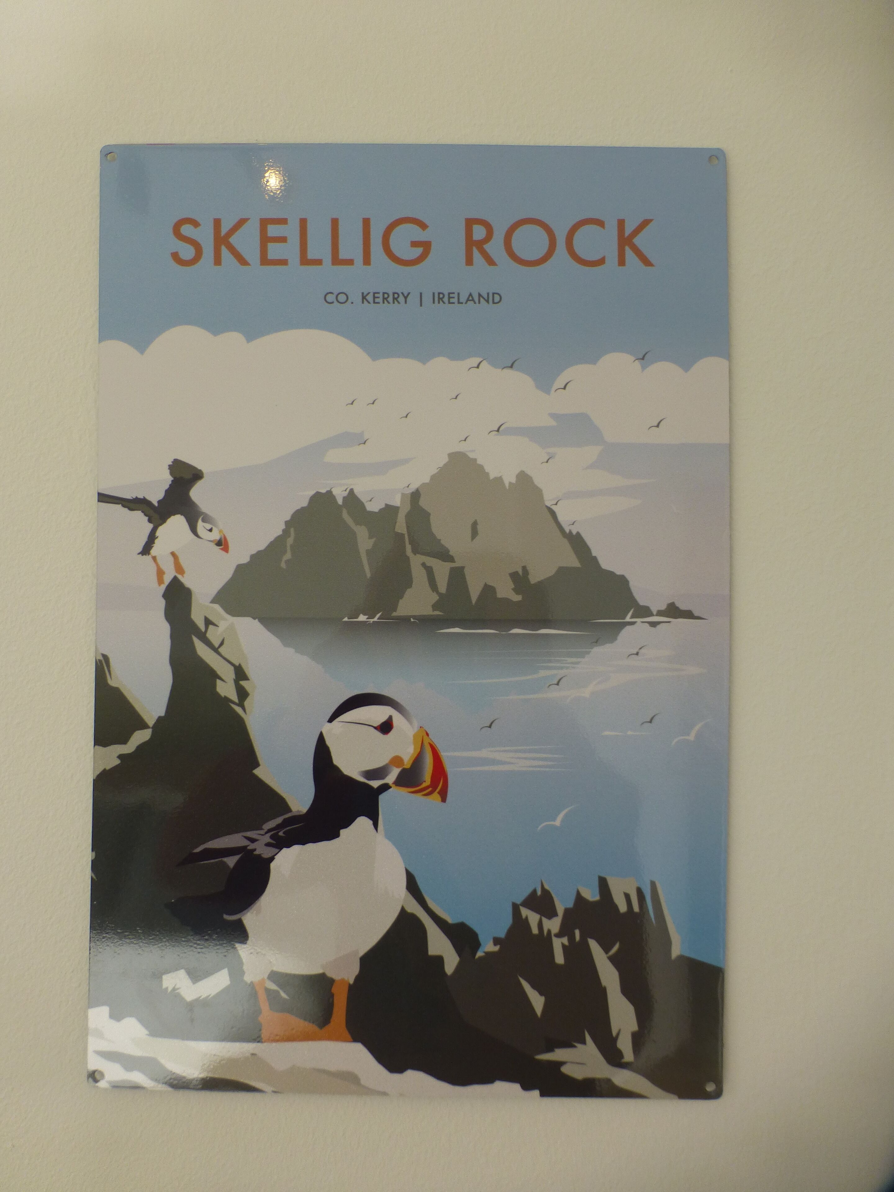 A poster with the text "SKELLIG ROCK CO. KERRY IRELAND" and a puffin bird on a rocky cliff.