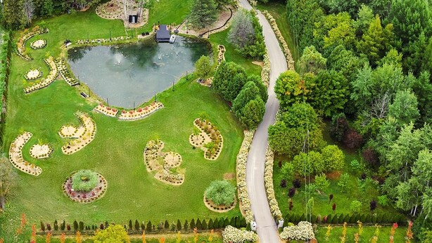 Vue aérienne d’un jardin aménagé avec un étang, une piscine et une maison.