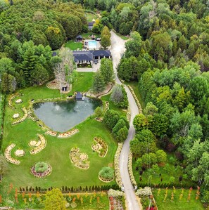An aerial view of a landscaped garden with a pond, a swimming pool, and a house. - Large Estate with Luxury Collection of Amenities  (Schomberg)