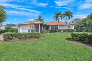 A single-story house with a red-tiled roof, a covered front porch, and a well-maintained lawn.