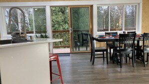 Eine Küche mit Spüle, ein Essbereich mit Tisch und Stühlen sowie eine Glastür zu einer Terrasse.