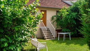 A house with a staircase leading to a door, a small table, and a bench in a grassy yard. - Homerez - House in Ferrières-Saint-Mary (Ferrières-Saint-Mary)