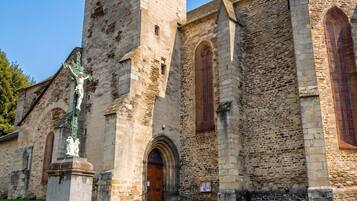 En historisk kyrka med ett högt klocktorn, välvda fönster och en staty i förgrunden.