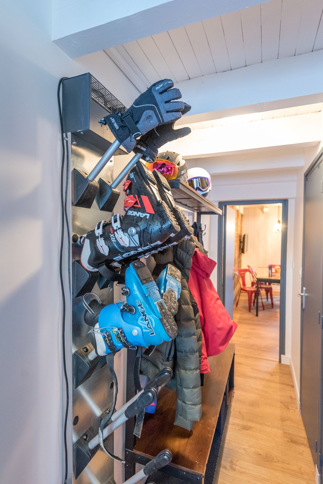 A wall-mounted rack with various winter sports gear, including skis, boots, and gloves.