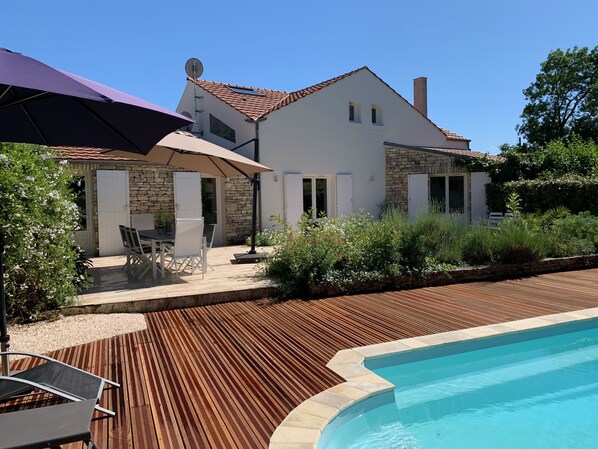 A house with a swimming pool, stone walls, and a patio with outdoor furniture.