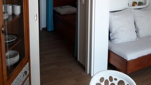 Pieni huone, jossa on sänky, pieni oleskelualue ja lasiovilla varustettu kaappi.