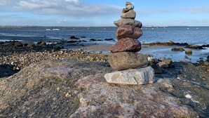 Un montón de piedras sobre una playa rocosa con el océano al fondo.