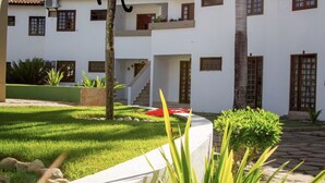 A white building with multiple windows and a staircase leading to an upper level. - Apartamento - La Corte (Porto Seguro)