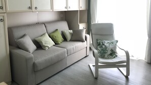 A modern living room with a grey sofa, white armchair, and patterned cushions. - Alice's House Luxury Hospitality - Elevator & Fast Wi-fi (Siracusa)