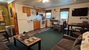 A living room with a sofa, a coffee table, and a television. - Majestic Recreational Lodging w/ Snowmobile and Side x Side rentals on Long Lake (Sinclair)