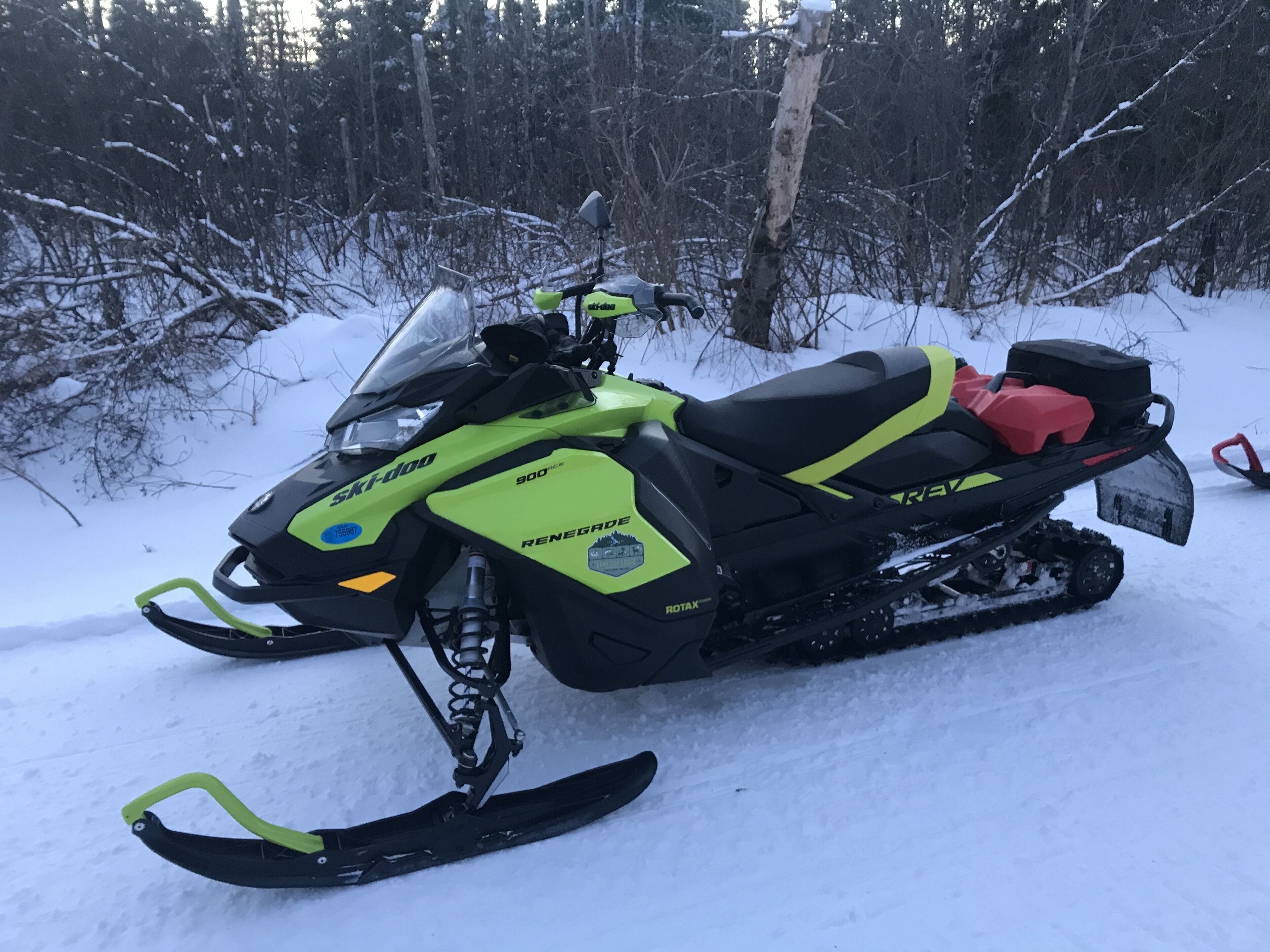 Un vehículo para nieve con diseño negro y amarillo neón, equipado con parabrisas y una caja de almacenamiento en la parte trasera.