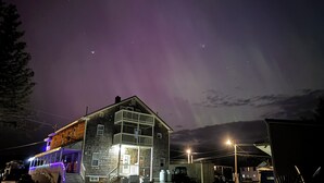 A two-story building with a balcony, a covered porch, and a garage. - Majestic Recreational Lodging w/ Snowmobile and Side x Side rentals on Long Lake (Sinclair)