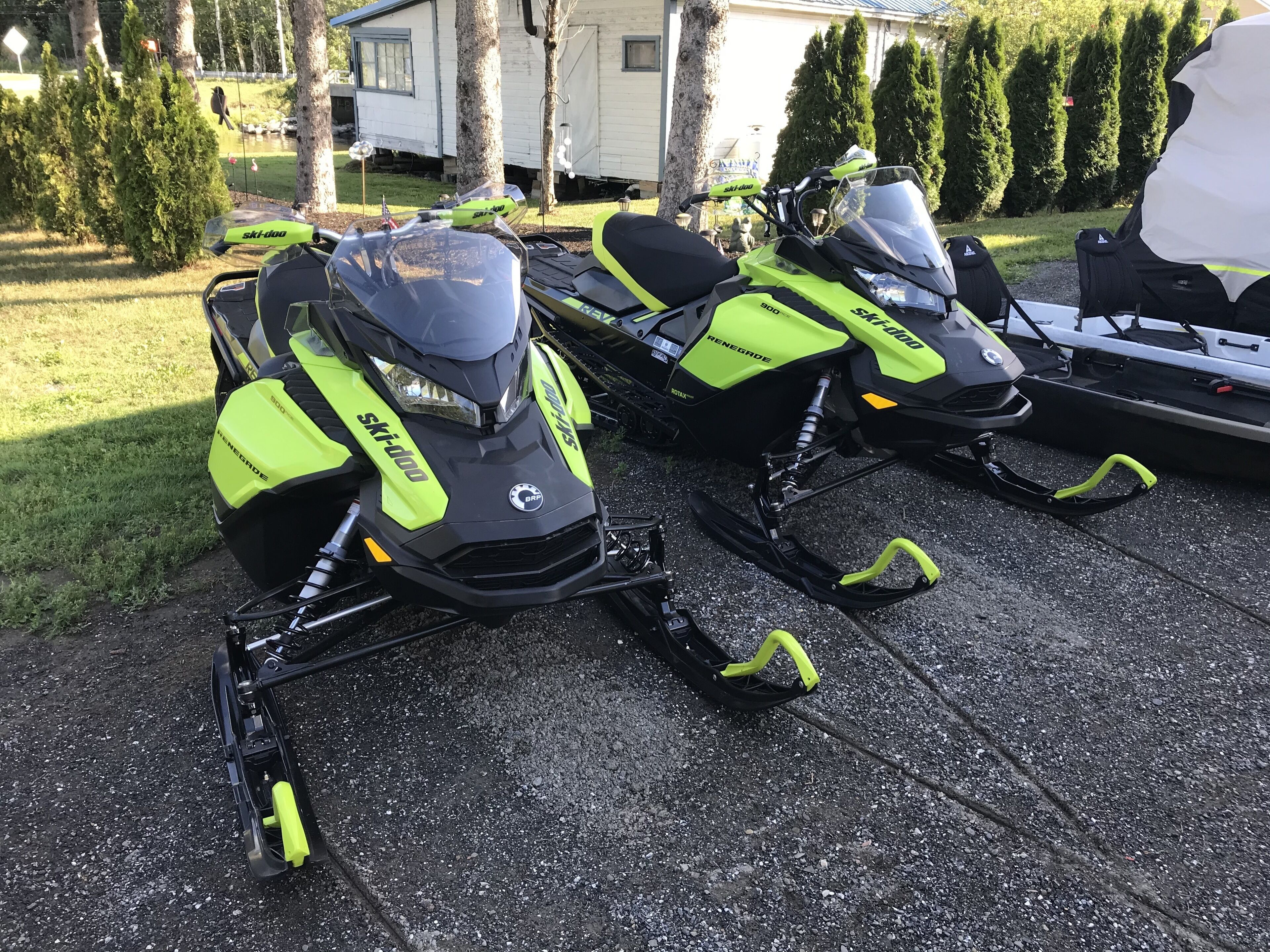 Dos motos de nieve estacionadas en un camino de entrada.