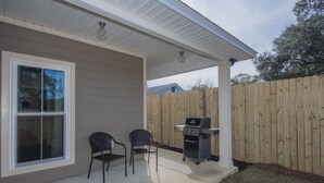 Un patio couvert avec deux chaises et un barbecue.