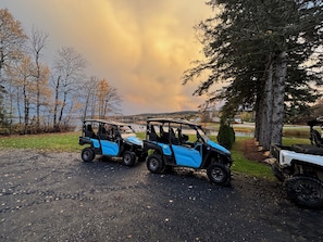 Two blue utility vehicles parked on a gravel path.