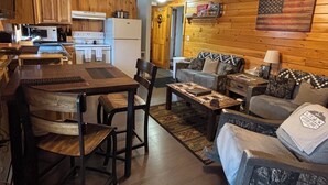 A cozy cabin interior with a dining area, kitchen, and living room. - Majestic Recreational Lodging w/ Snowmobile and Side x Side rentals on Long Lake (Sinclair)