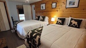A hotel room with two beds, a ceiling fan, wooden panel walls, and a framed picture. - Majestic Recreational Lodging w/ Snowmobile and Side x Side rentals on Long Lake (Sinclair)
