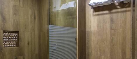 A modern bathroom with a glass shower enclosure, a toilet, and a towel rack.