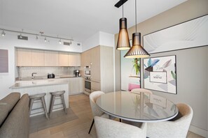 A modern kitchen with a central island, bar stools, and pendant lighting. - Panoramic bay views meet modern elegance in this 1-bedroom retreat (Hollywood)