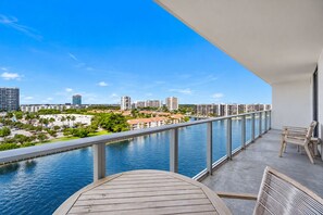 Ein Balkon mit Blick auf einen Fluss, eine Stadtlandschaft und einen Holztisch.