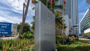 A sign for Hyde Beach House with a modern design, surrounded by lush greenery and palm trees. - Panoramic bay views meet modern elegance in this 1-bedroom retreat (Hollywood)