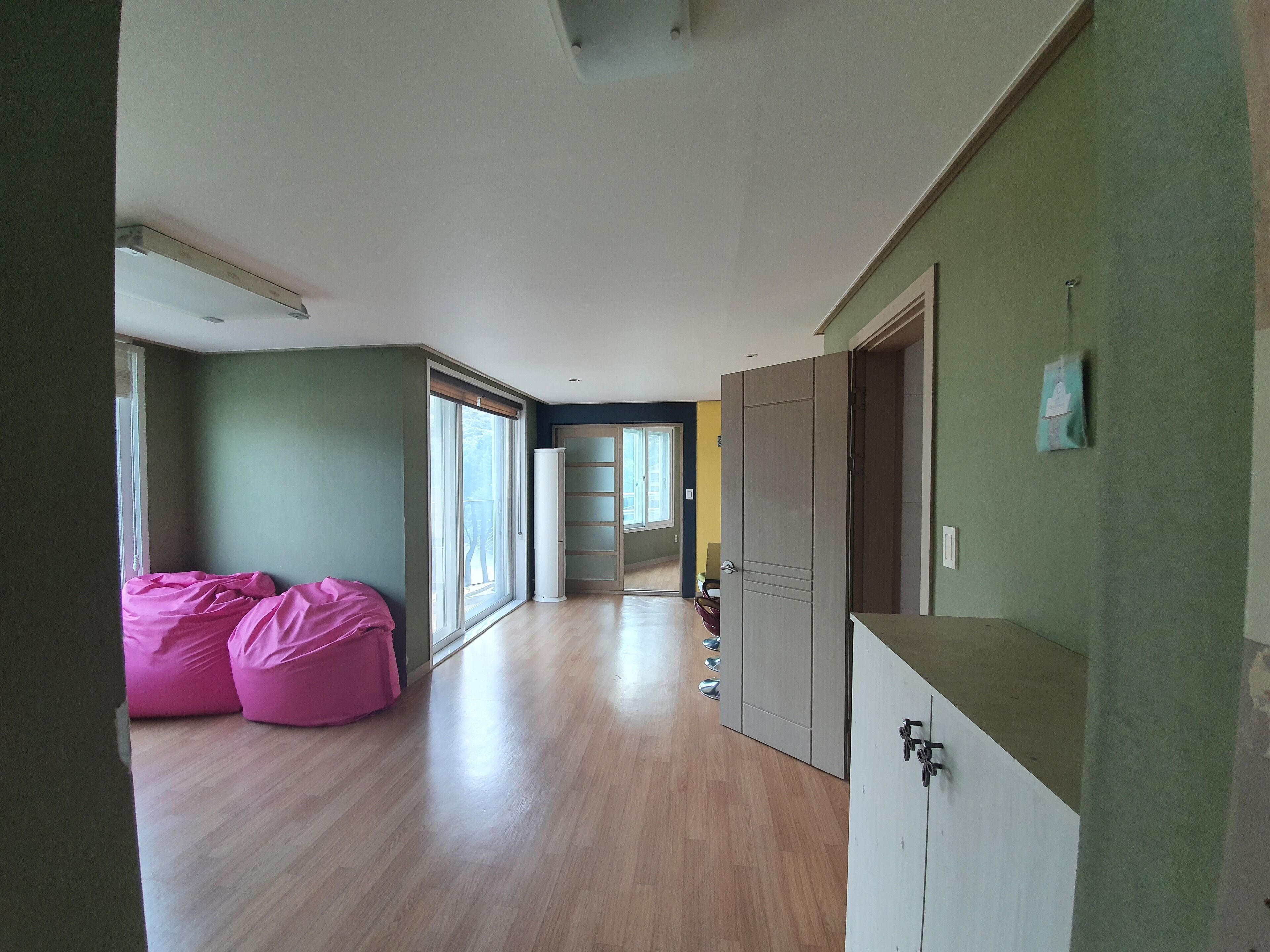 Una habitación amplia con piso de madera, puerta corredera y ventana grande.