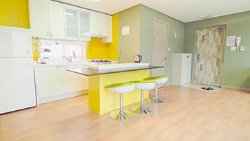 A modern kitchen with white cabinets, a yellow island, and three bar stools.