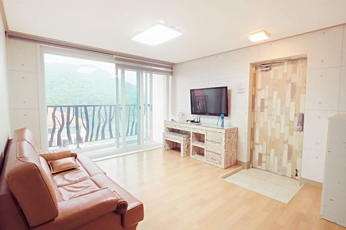 Un salon moderne avec un canapé en cuir, un téléviseur à écran plat et un meuble en bois.